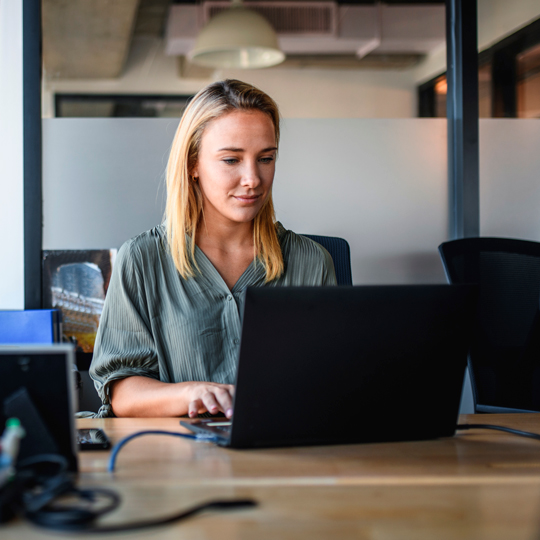 Woman sitting in an office setting and working on a computer