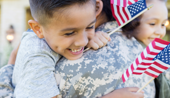 Child holding American flags while smiling and hugging an adult