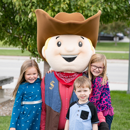 Lil' Buckaroo Savings Club cowboy mascot with three kids