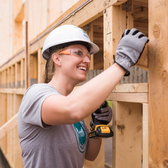 Woman building the wooden frame of a house