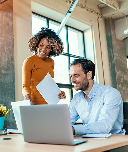 Man and woman working together in an office setting and smiling