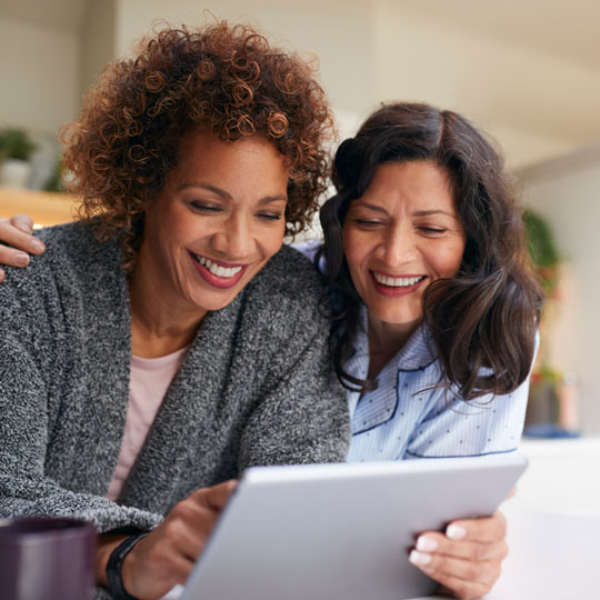 Two women smiling and looking at a tablet
