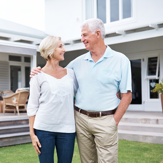 Older couple standing and looking at each other in front of a house