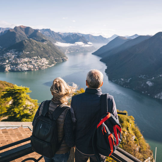 Man and woman looking away from camera and out at mountains and river